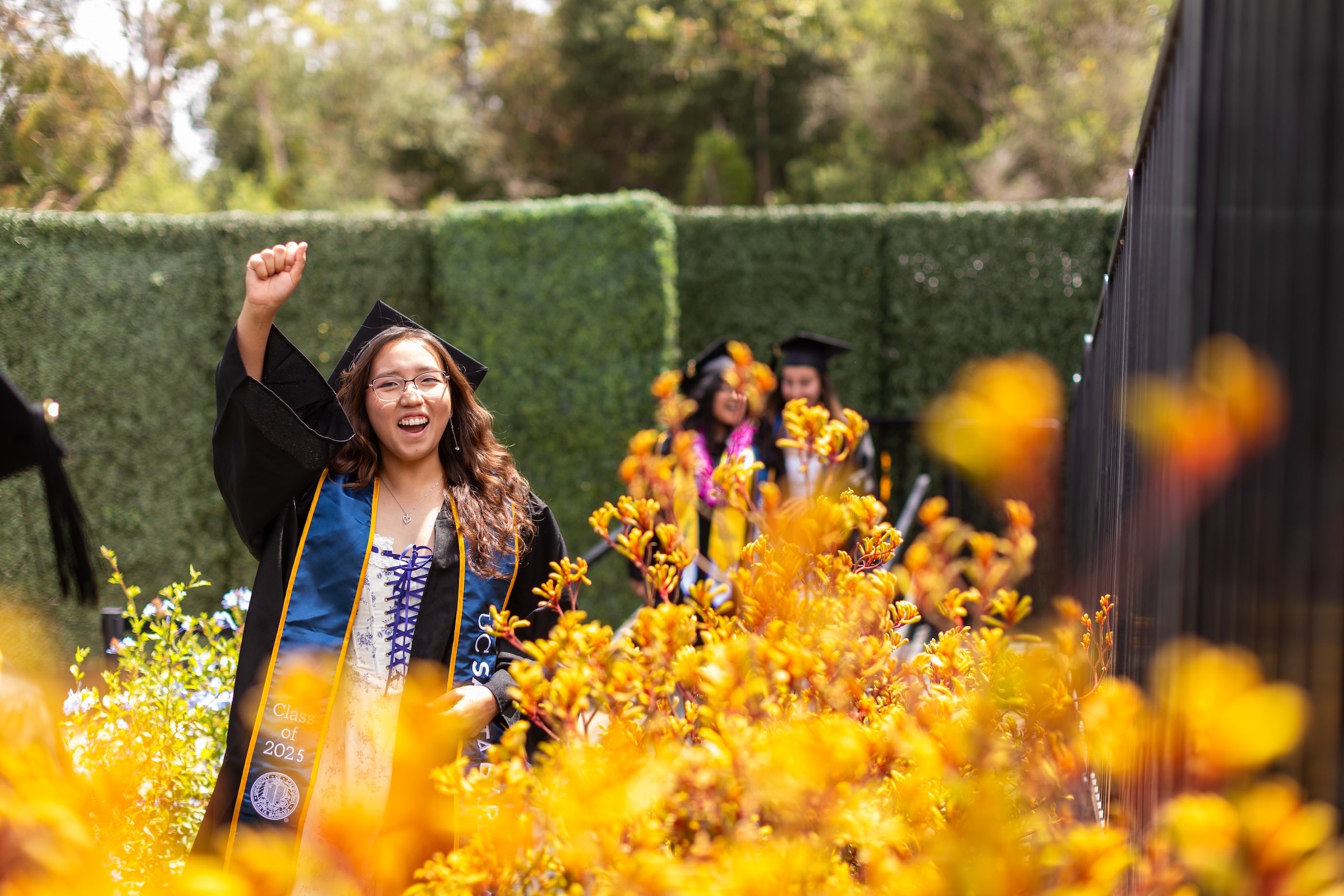 student in cap and gown smiling and walking to get diploma